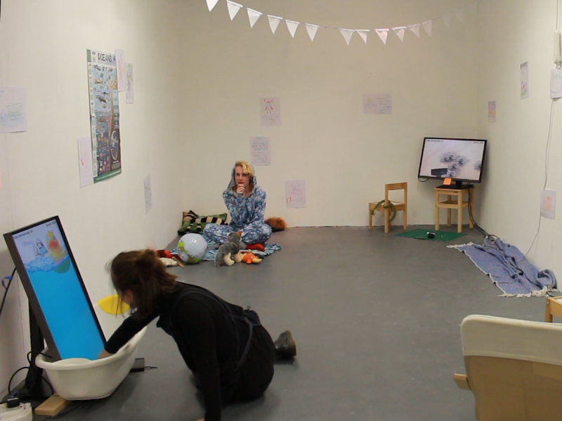 A room with three different screens, each showing different minigames. In the corner, an actor is pretending to be a child.